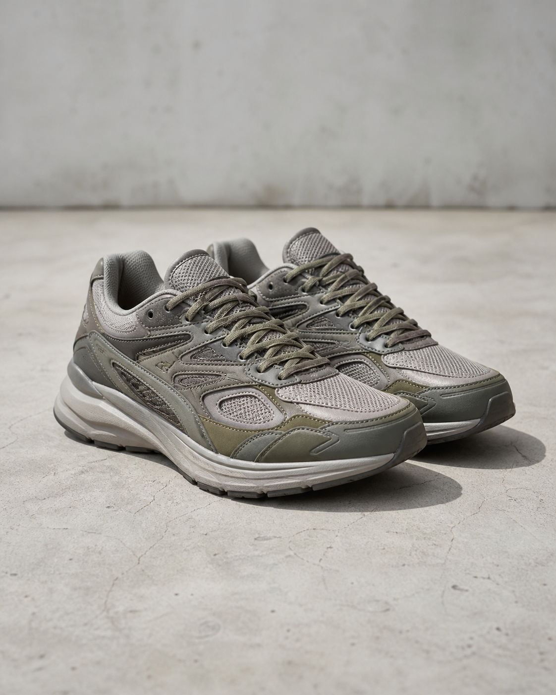 Sneaker Arc Runner ash y olive con malla en capas, fotografía de producto en estudio.