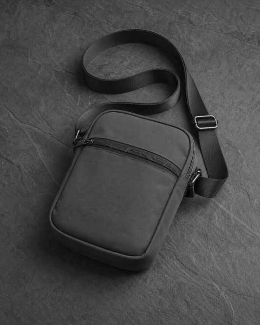 Bolsa Orbit Crossbody graphite de nylon mate con cierre liso, fotografía de producto en estudio.